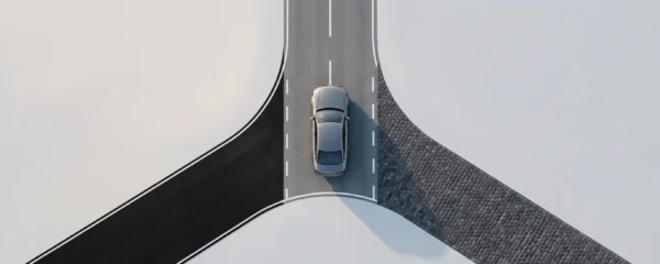 Vue aérienne d'une voiture moderne positionnée à un carrefour face à trois routes différentes, symbolisant le choix entre solutions de financement automobile